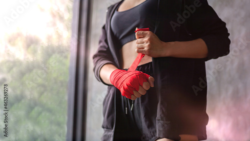 A female boxer wrapped a boxing cloth on both hands.