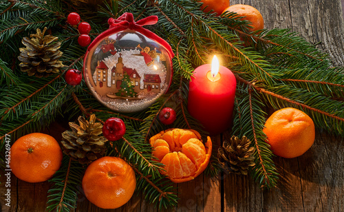  Christmas New Year composition with tangerines. red burning pine cone candle on a dark wooden background. 