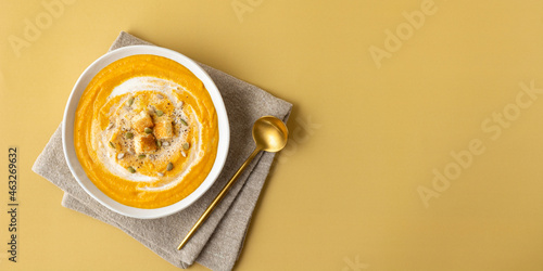 Pumpkin soup with toast and seeds on a beige background isolated banner. Autumn vegetables, healthy food.
