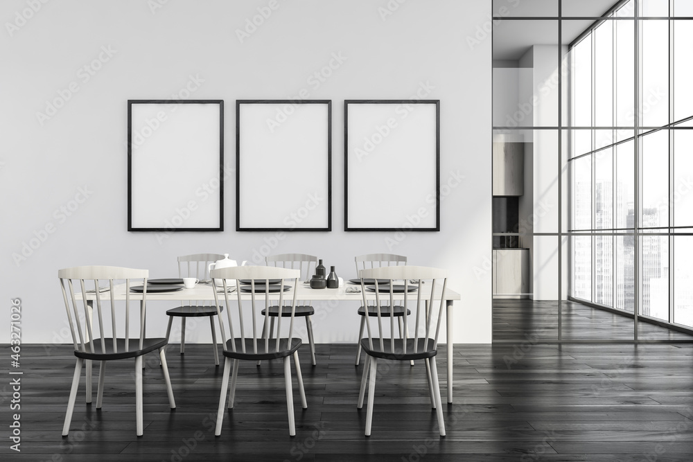 Three frames on white wall of dining room with black wood floor