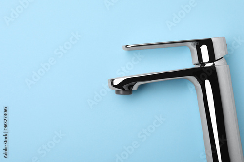 Single handle water tap on light blue background  top view. Space for text