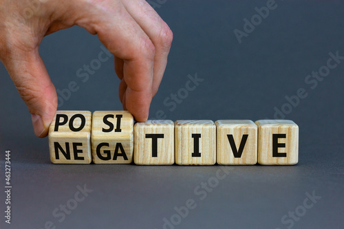 Positive or negative symbol. Businessman turns wooden cubes and changes the word 'negative' to 'positive'. Beautiful grey table grey background. Business, positive or negative concept. Copy space.
