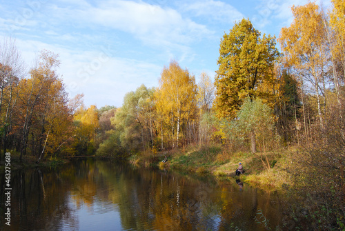 Autumn lake. Forest, fishermen fishing on the autumn lake. The lake is surrounded by trees with yellow foliage. Late autumn. Autumn landscape. Russia. © Julia