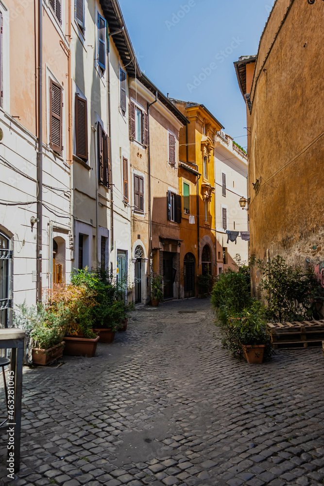 An alley leading through the traditional homes in the Trastevere neighborhood of Rome on a bright sunny day.