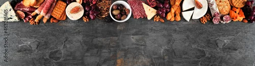 Panel kuchenny z motywem Assorted cheese and meat appetizers. Overhead view top border on a dark slate banner background with copy space.