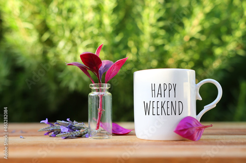 coffee cup with the text happy weekend on wooden table outdoors photo