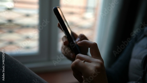 Woman typing on smartphone device at home. Person sending message or email.