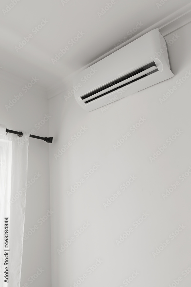 Flat air conditioner on white wall in room interior