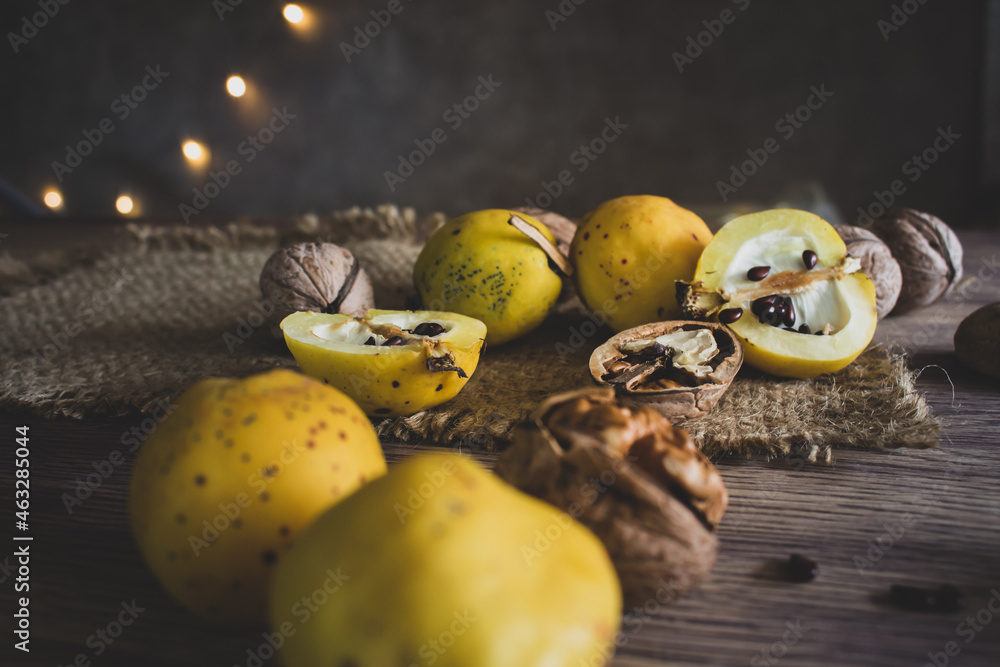 Quince apple and nuts on wooden table. Autumn harvest concept. Autumn rustic still life. Quince fruits with seeds and walnuts. Ripe organic food. Seasonal dessert.