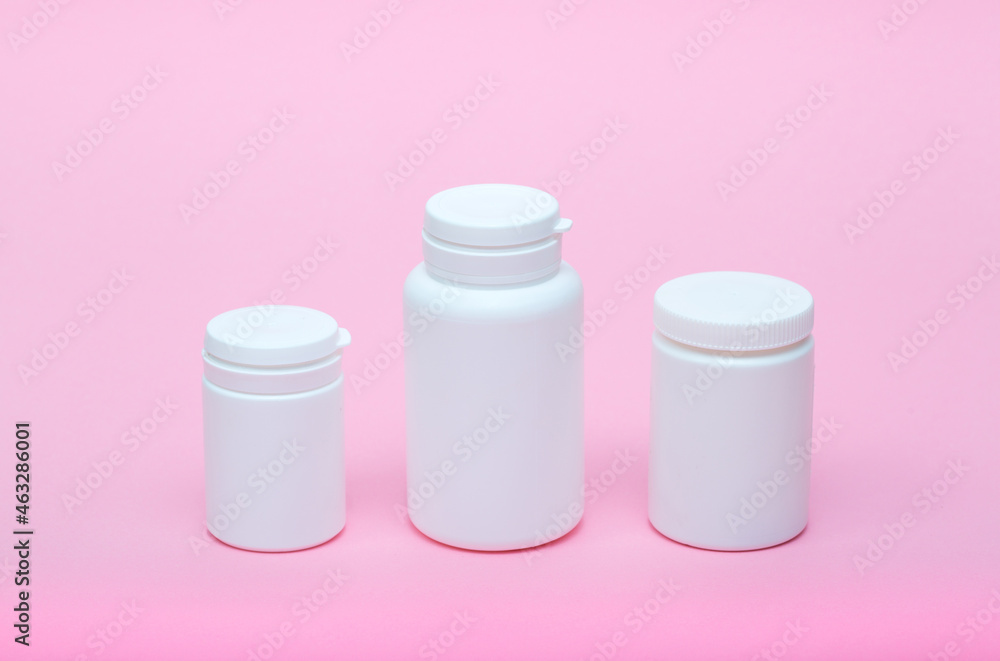 White different medecine or cosmetic jars on a pink background as a concept of cosmetology of medecine and treatment White different medecine or cosmetic jars on a pink background as a concept of cosmetology of medecine and treatment