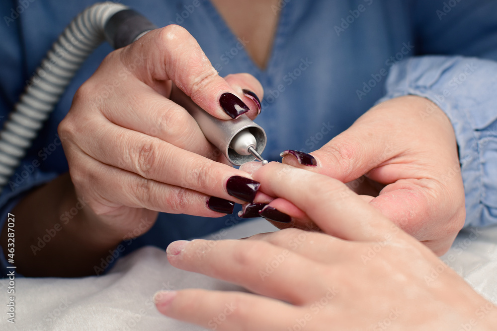 Manicure. Treatment of the nail plate by a manicure master. The girl is doing manicure, beauty, beauty, varnishing, polishing the nail plate. Beauty salon, manicure master. How to do 