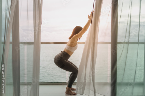 Close up of Asian woman do yoga pose on the balcony with sea view.