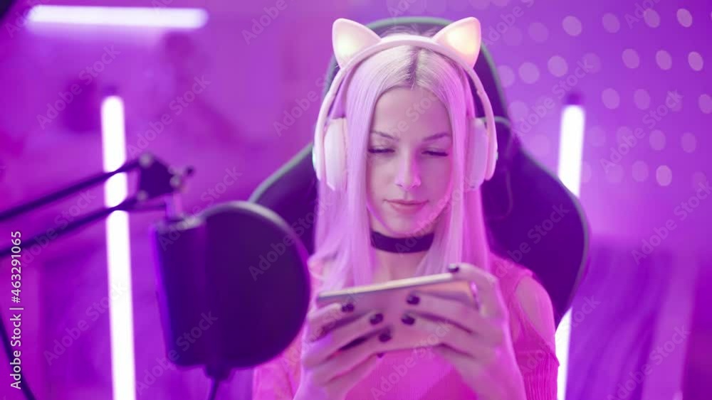 Portrait of cute Gamer Girl with microphone streaming playing on smartphone 4K Portrait of cute Gamer Girl with microphone streaming playing on smartphone 4K