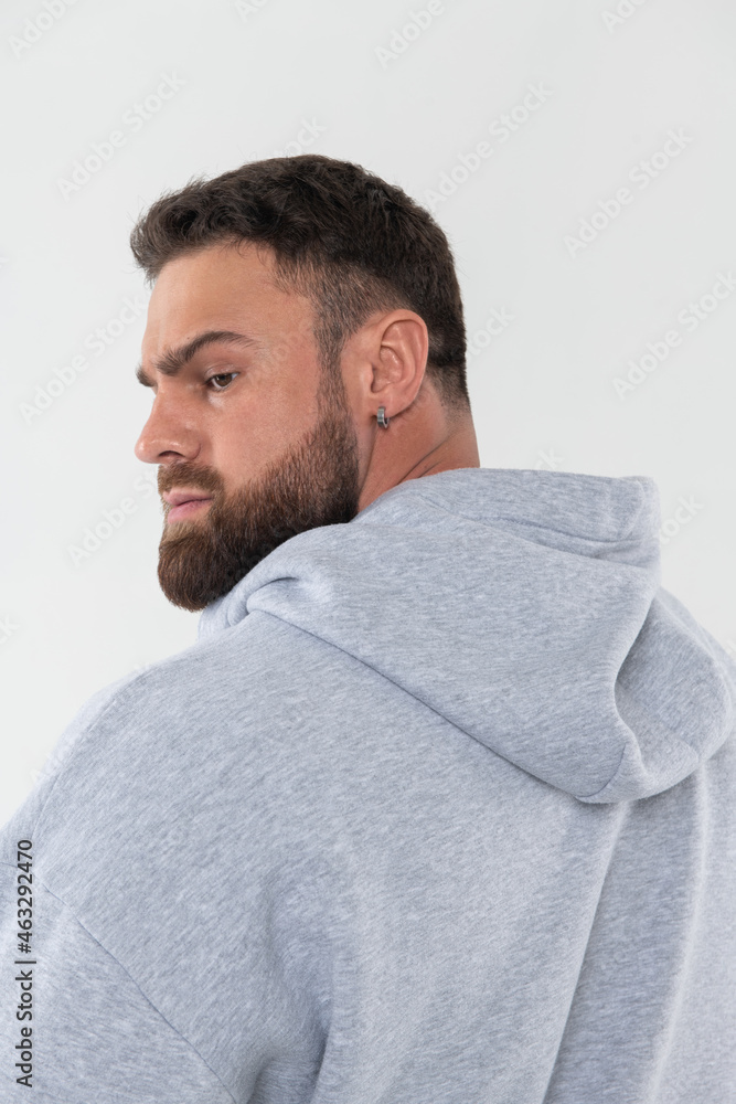 Fototapeta premium Profile portrait of handsome bearded guy with earring and grey hoodie