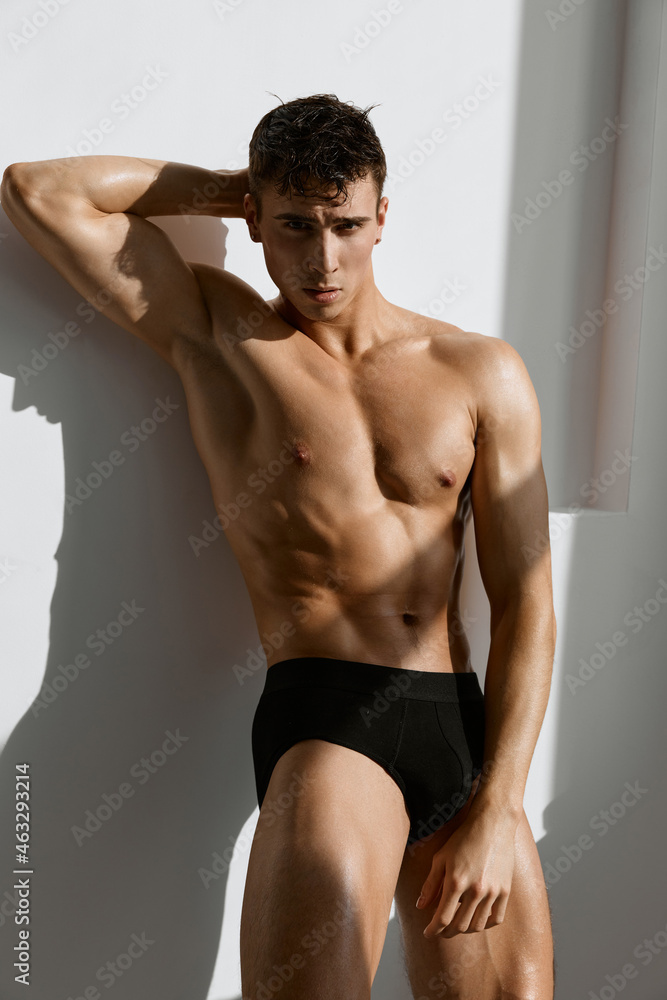 Obraz premium man with a naked pumped up body in black panties light background