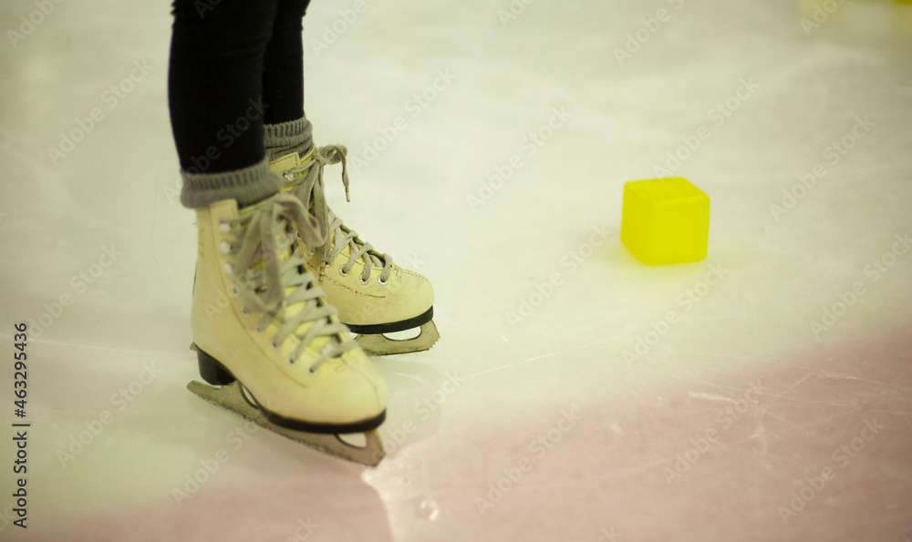 Little girl learns to skate. Children's skates. A child training on ice. The concept of children's figure skating. Children's sports. Winter sport Little girl learns to skate. Children's skates. A child training on ice. The concept of children's figure skating. Children's sports. Winter sport
