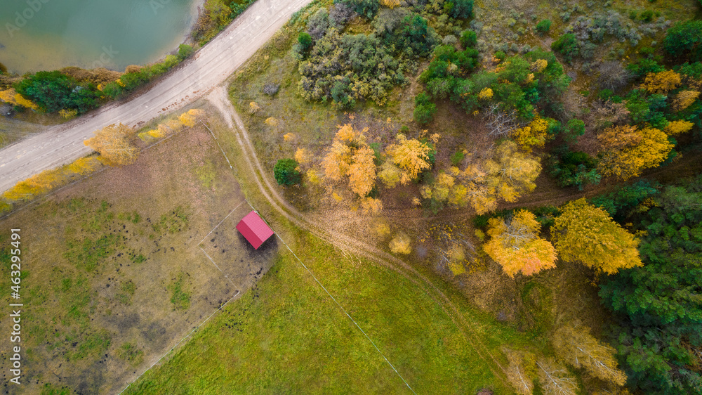 Little lake or pond of unusual shape with a beautiful autumn nature, small house and gravel road photographed from above with a drone. Real is beautiful Little lake or pond of unusual shape with a beautiful autumn nature, small house and gravel road photographed from above with a drone. Real is beautiful