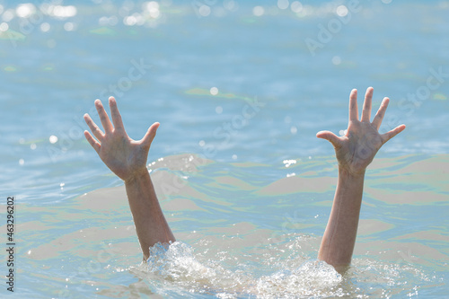 A hands from under the water of a drowning girl, help and urgent rescue of a person during a dangerous swimming, sos photo