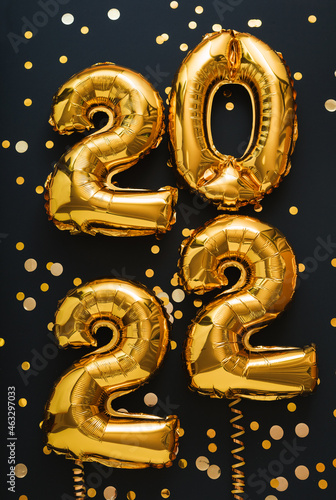 2022 year gold balloon on black background with golden ribbons Festive confetti. Happy New year eve invitation with Christmas gold foil balloons 2022 text vertical gift card photo