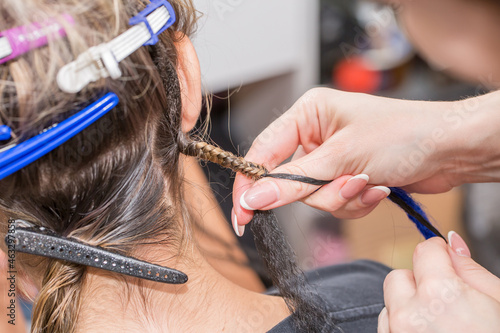 Dreadlocks African braids are weaved by a master hairdresser in the salon, head and hair close-up braided into dreadlocks copy space, boy european