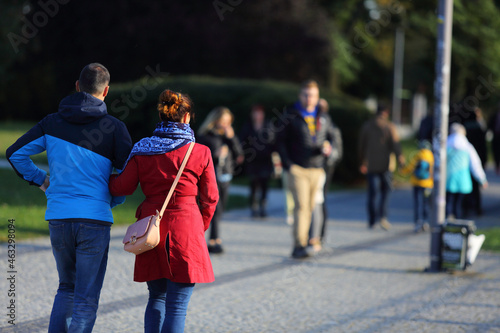 Para młodych ludzie, kobieta i mężczyzna spaceruje deptakiem, chodnikiem w parku.	