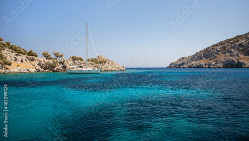 Yacht on anchor in turquoise sea water between rocky seashore islands
