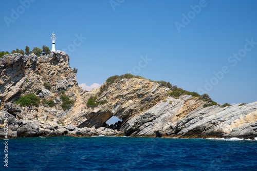 Fototapeta Naklejka Na Ścianę i Meble -  Rocky island with lighthouse and grotto in blue sea 