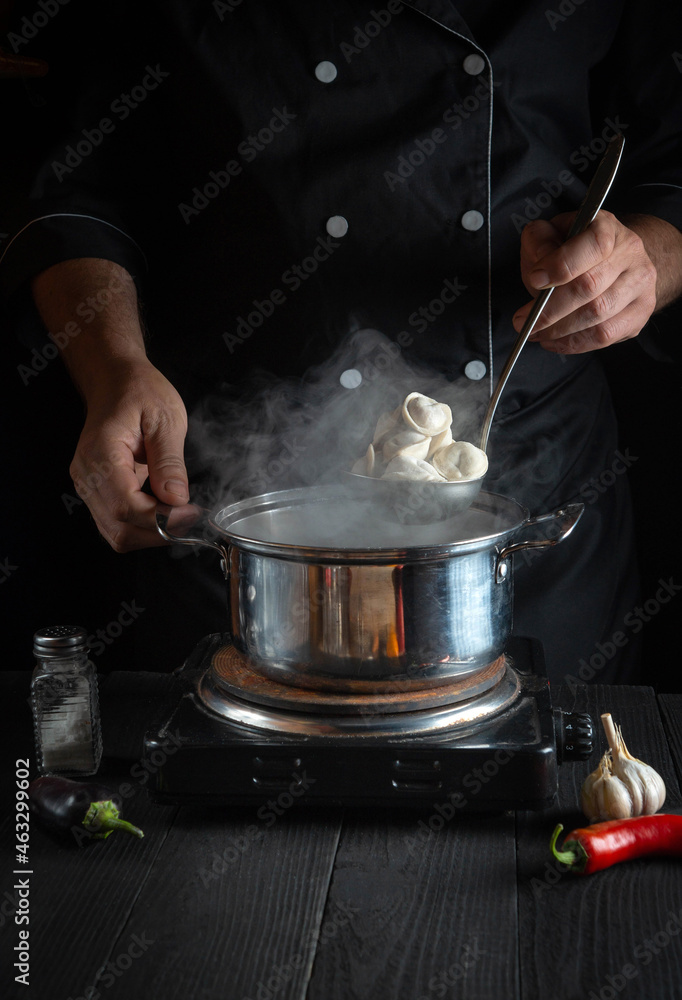 Chef cooks meat dumplings in a saucepan in the restaurant kitchen. Close-up of hands of the cook during work Chef cooks meat dumplings in a saucepan in the restaurant kitchen. Close-up of hands of the cook during work