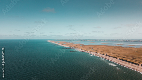 Aerial drone view of endless ocean beach with white sand and grass dunes. Panorama beach wild nature on a warm summer vacation day. Ocean coastline landscape in Denmark and Netherlands in Europe © Ricardo