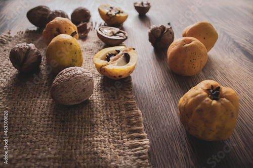 Quince fruits and walnut on wooden table. Autumn harvest concept. Autumn rustic still life. Wild quince apples with seeds and nuts. Ripe organic food. Seasonal dessert.