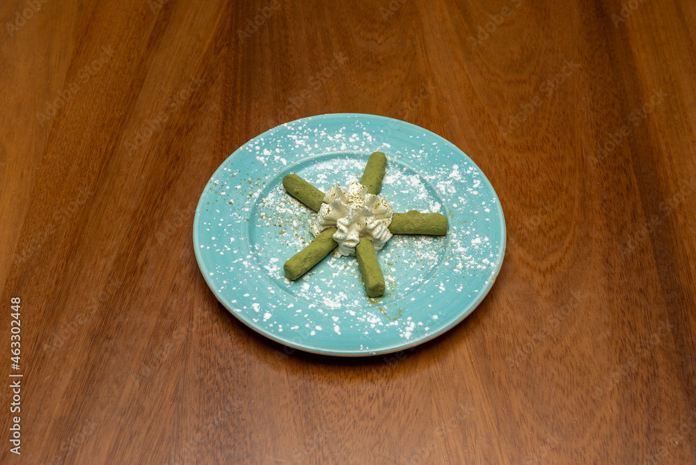 green tea chocolates with whipped cream, icing sugar on a blue plate and a dark wooden table green tea chocolates with whipped cream, icing sugar on a blue plate and a dark wooden table