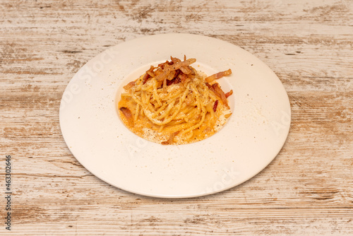 Delicious spaghetti dish with carbonara sauce and guanciale with grated parmesan cheese on white plate