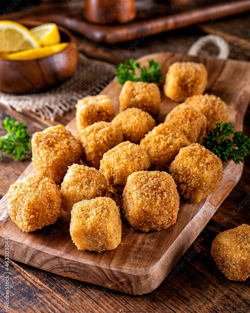 Fotografie Delicious breaded fish nugget snacks on a rustic wood table top.