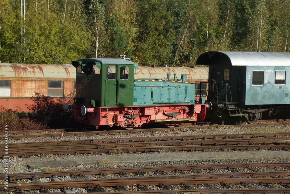 Alte grüne Rangierlokomotive auf einem Abstellgleis. Viele alte Fahrgastwagen sind zu sehen. 