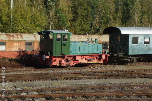 Alte grüne Rangierlokomotive auf einem Abstellgleis. Viele alte Fahrgastwagen sind zu sehen. 