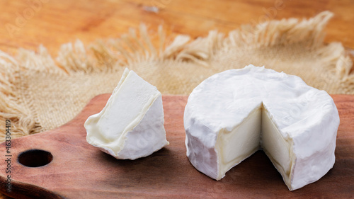 Camembert cheese on a wooden cutting board. White cheese on a wooden background. Copy space