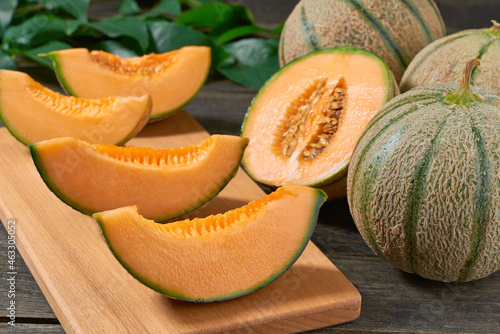 sliced cantaloupe melon on wood plate and old wooden background.