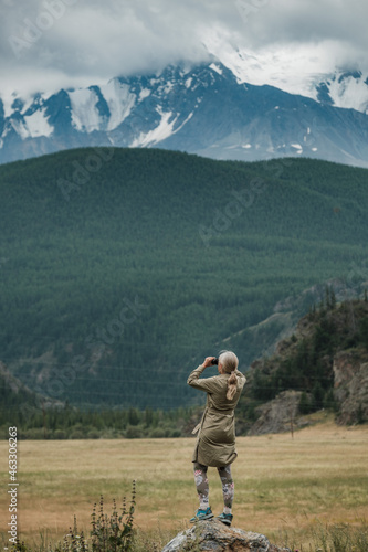 Girl with binoculars standing in the mountains of the Altai Republic