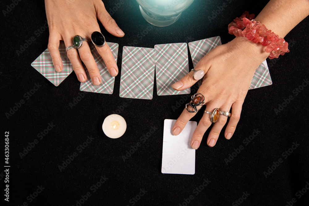 Fortune teller or witch hands, cards, candles and a glowing magic ball