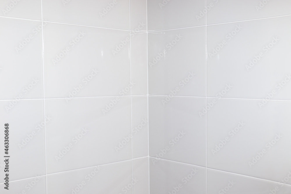 Milky white tiles on the bathroom wall. Docking tiles in the corner, renovation and improvement of housing