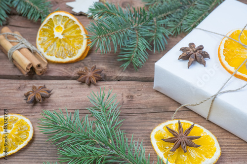 Christmas presents or gift box wrapped in kraft paper with decorations, pine cones, dry orange orange slices, cinnamon and fir branches on a rustic wooden background. Holiday concept.