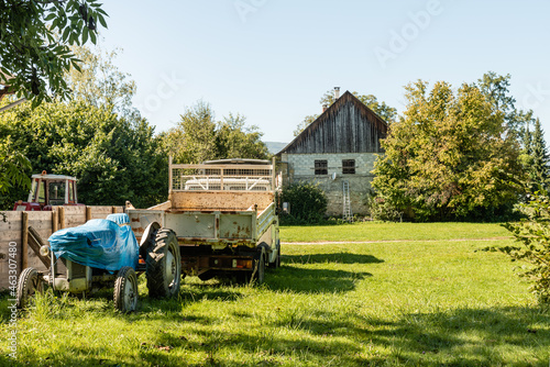 Old barn, tractor and farm machinery in green field © PGS