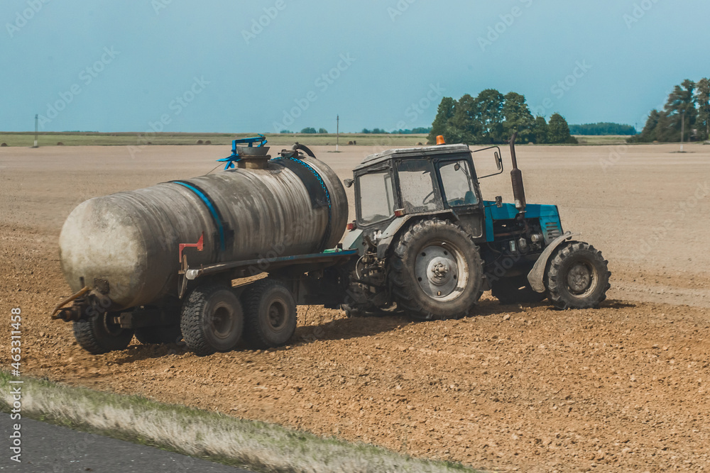 Obraz premium Tractor with a barrel of fertilizer in the field. Agricultural equipment and industrial work on the farm