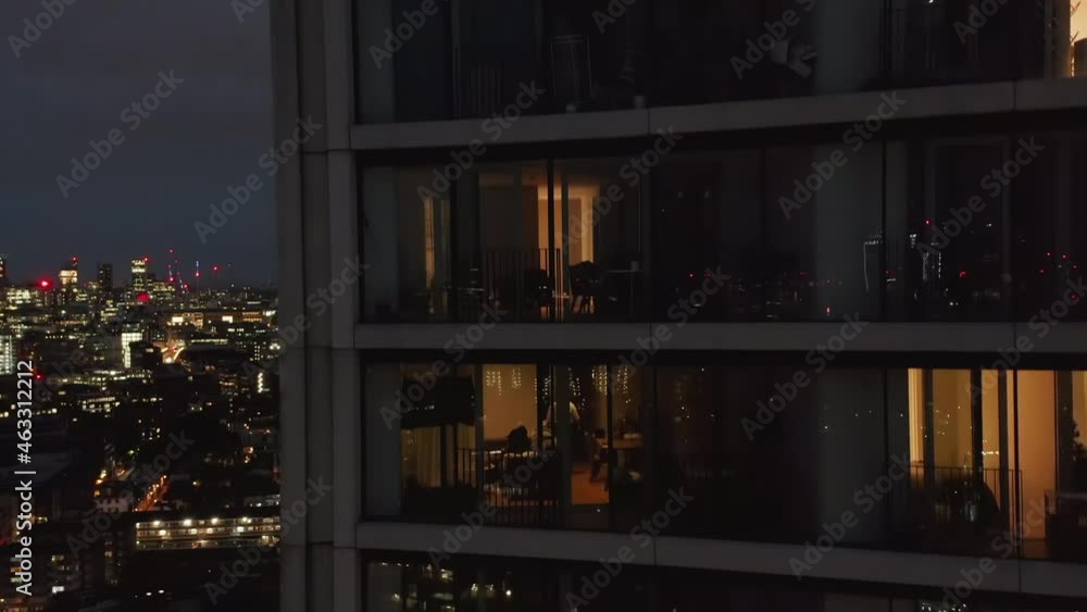 Luxury apartment in modern tall residential building at night. Close up view of into windows. Crane up shot. London, UK Luxury apartment in modern tall residential building at night. Close up view of into windows. Crane up shot. London, UK