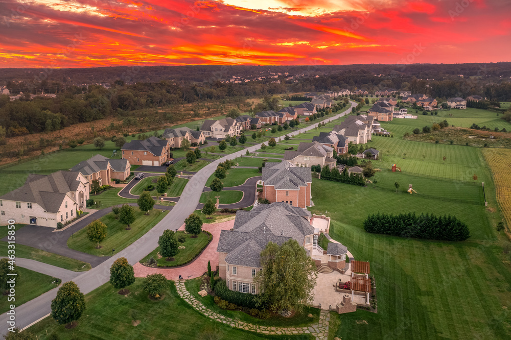 Aerial view of new construction winding dead-end street lined with luxury houses, large lots,  in upper class neighborhood American real estate development in the USA with stunning sunset orange sky - obrazy, fototapety, plakaty 