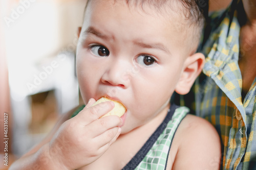 Close-up of cute baby boy face enjoying eating snacks.