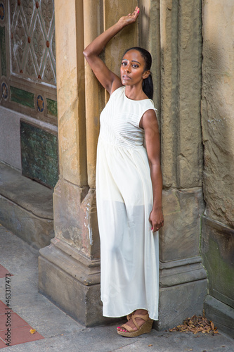 Obraz na płótnie Dressing in white long dress, a young pretty girl is standing by an ancient wall, lonely and sad.. w salonie