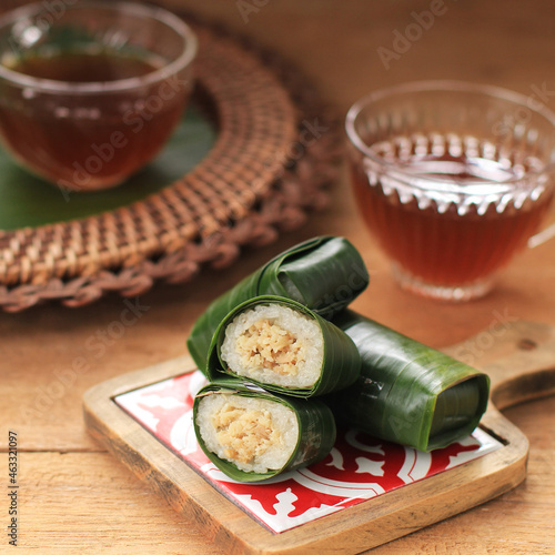 Lemper Ayam Served with Tea. Lemper is  Indonesian Snack Made of Glutinous Rice Filled with Seasoned Shredded Chicken Wrapped in Banana Leaf, Served for Tea Time