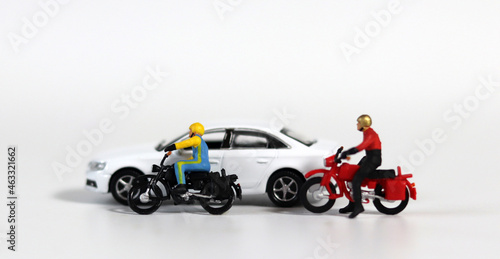 Miniature people and miniature car. White cars and fallen motorcycle drivers. Concept about the dangers of speeding motorcycles. 