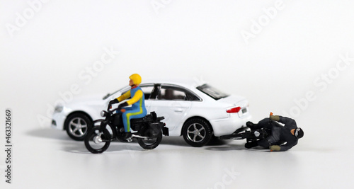 Miniature people and miniature car. White cars and fallen motorcycle riders. Concept about the dangers of speeding motorcycles. 